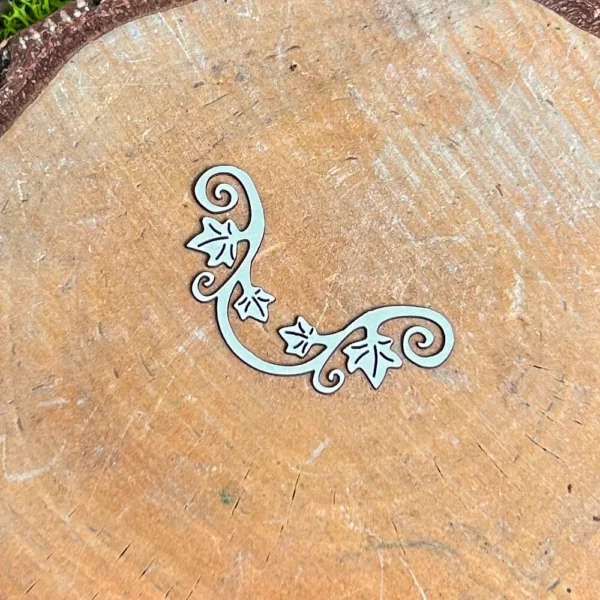 Ornament z liśćmi bluszczu wycięty z białej tektury 1,5 mm na drewnianym tle